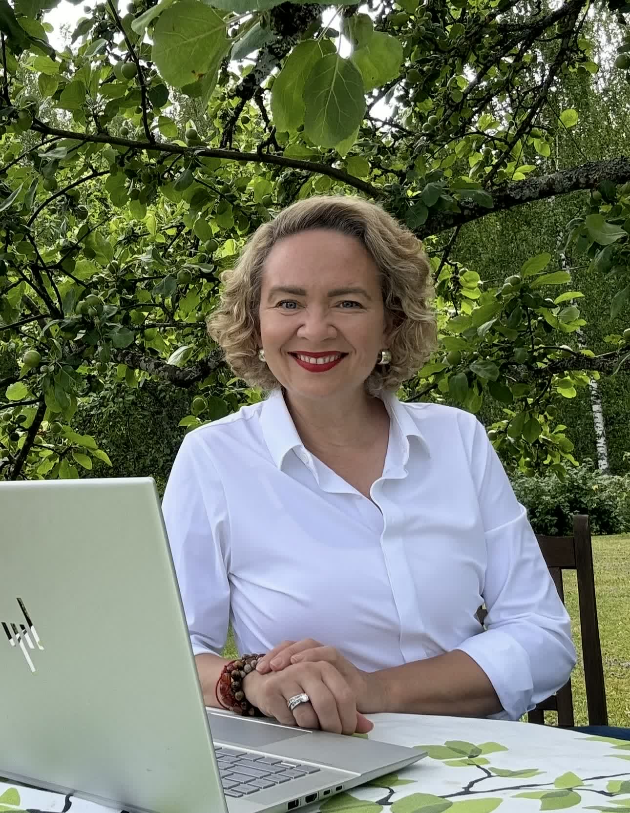 Tarja Stephens working on a laptop under an apple tree in a Finnish garden