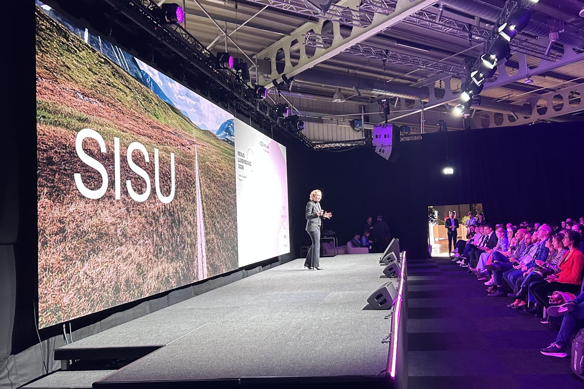 Tarja on stage in front of a full audience, the word Sisu across the screen