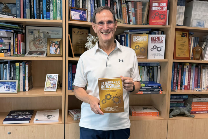 A reader holding the book in front of a wall of books.